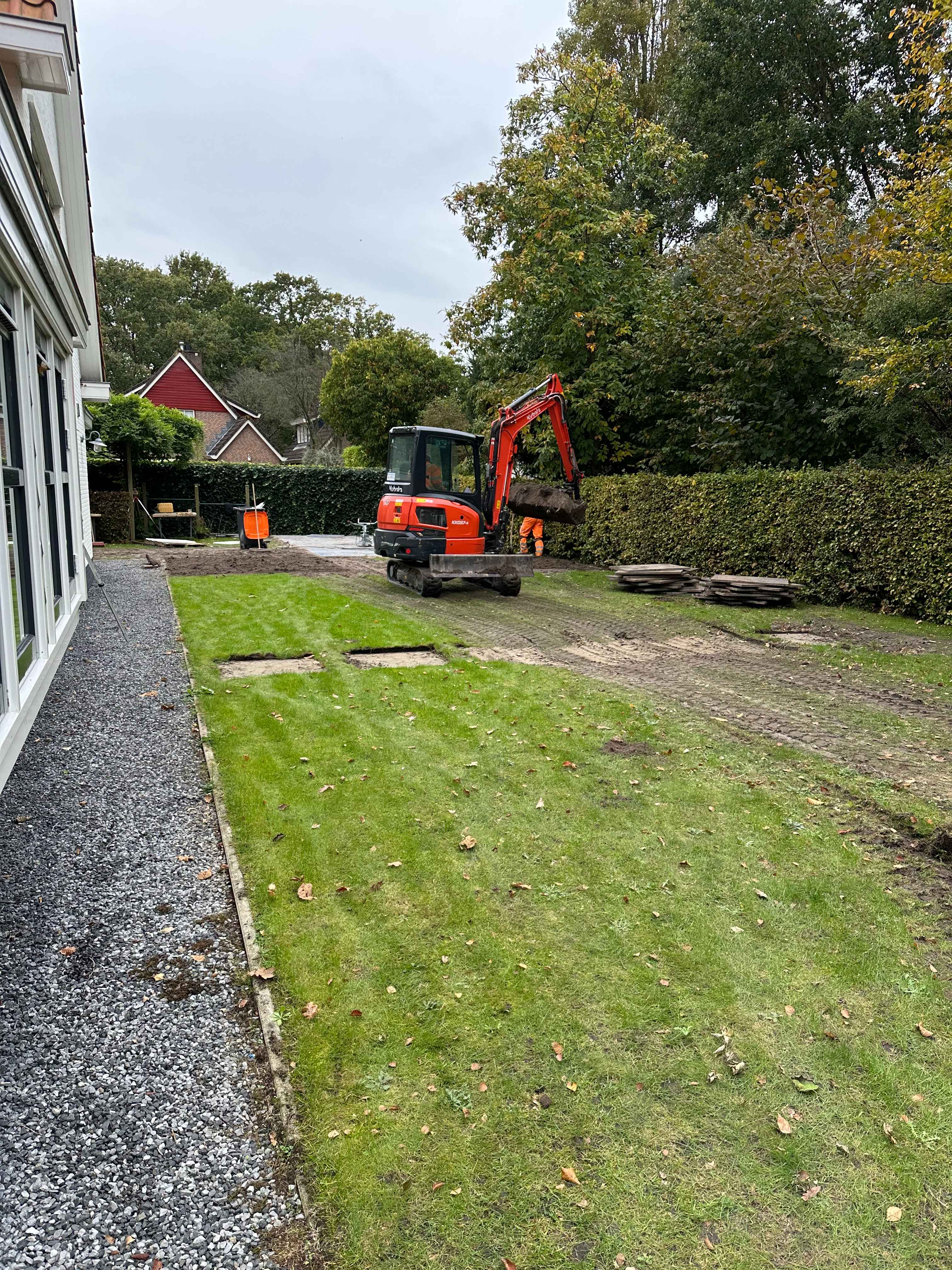 Tuin met een oranje graafmachine