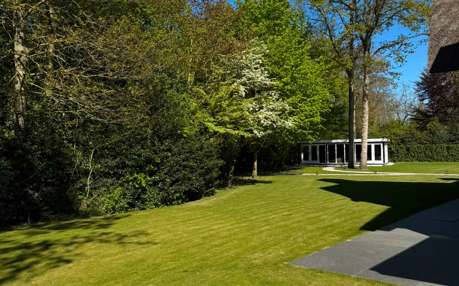 Strak gemaaid gazon met verzorgde borders en bomen, aangelegd door Homeservices